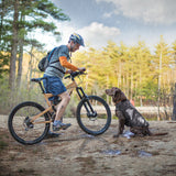 man on bicycle next to dog in dog jacket 